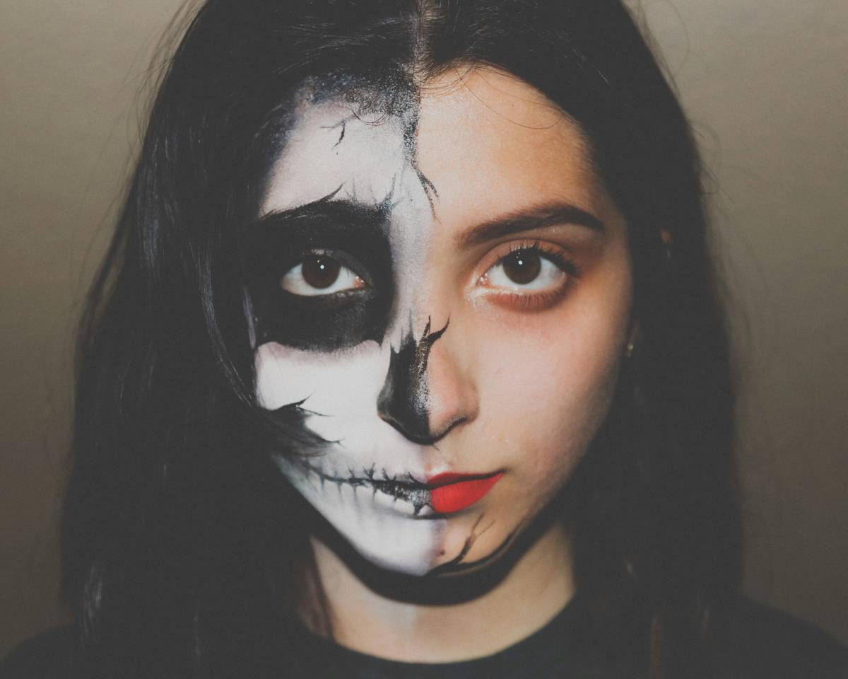 halloween demon makeup with cracked red paint and smudged black details on model's face