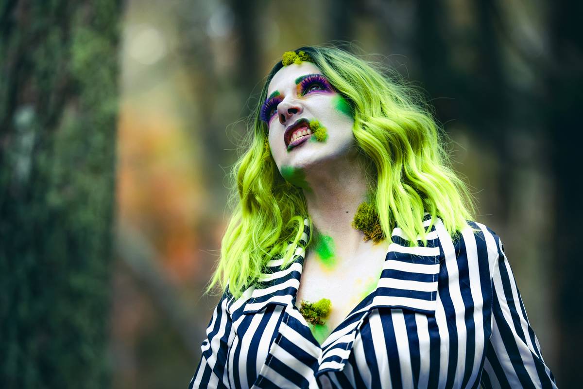 Close-up of halloween spider makeup showing detailed leg lines and glossy black carapace on model's face